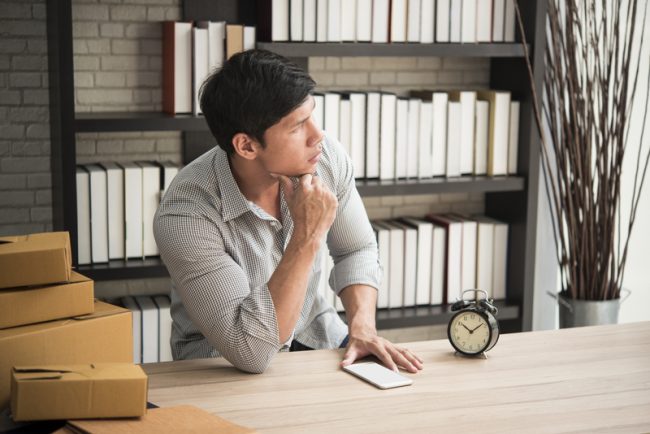 Young man sitting in a home office with thinking. sme, owner ent