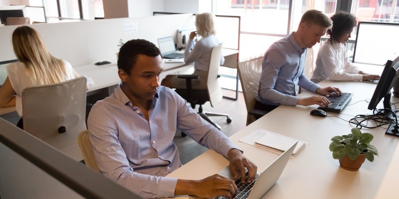 Multicultural staff business people sitting at desks working in office