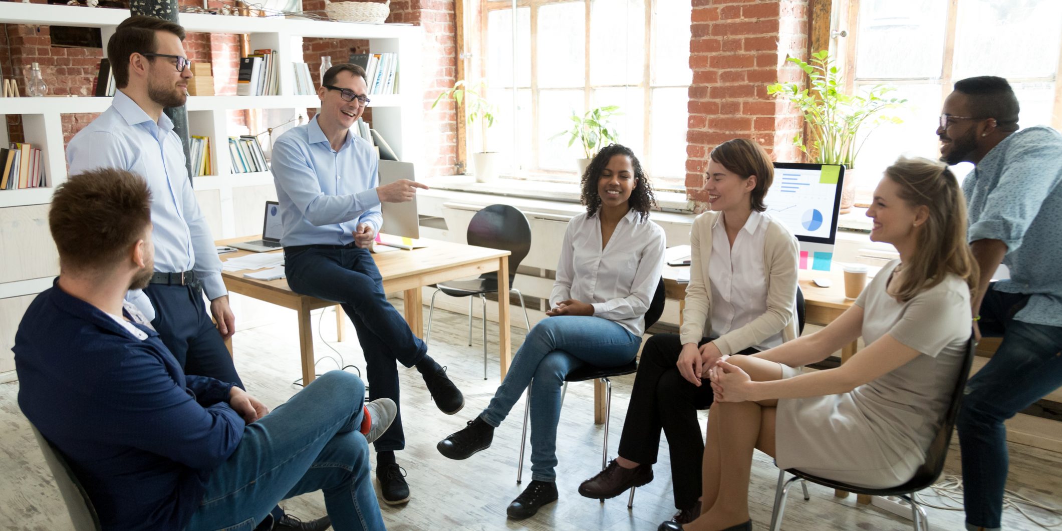 Happy coach laughing at employee joke at briefing