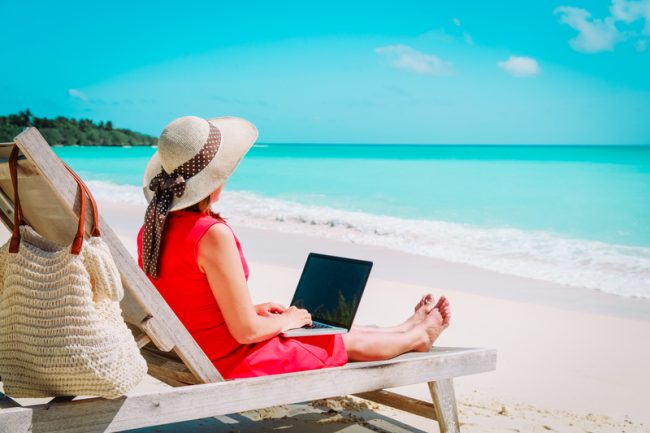 remote work concept -young woman with laptop on beach