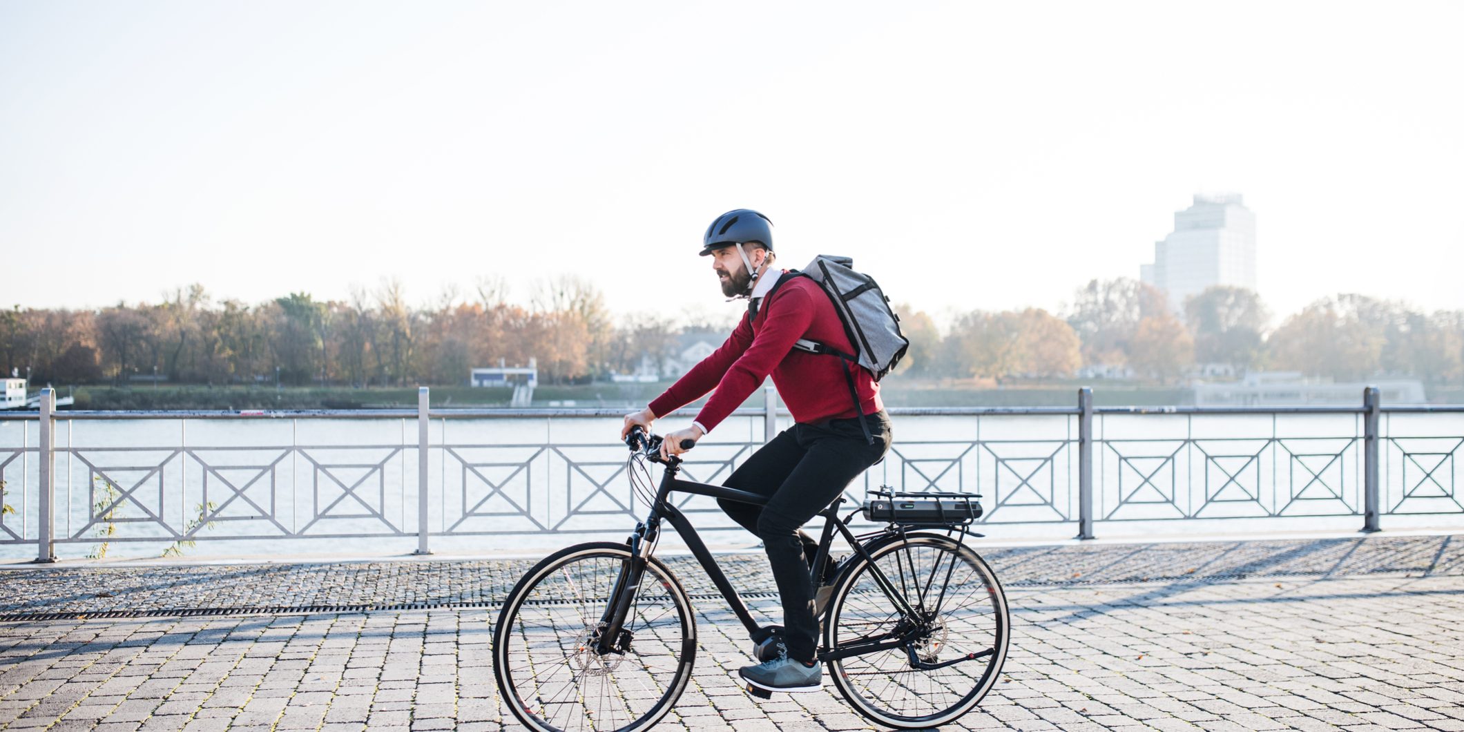 Hipster businessman commuter with electric bicycle traveling to work in city.